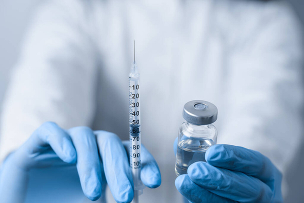 Γιατρός που κρατάει το εμβόλιο του κορωνοϊού. Εμβολιασμός Covid-19. Σταματήστε την καραντίνα. Κοντινό πλάνο suringe και φαρμακευτική αγωγή - Φωτογραφία, εικόνα