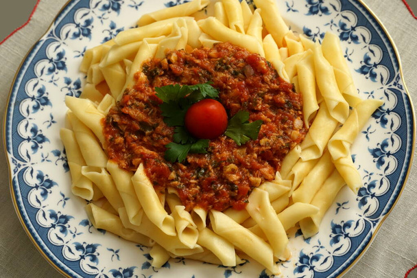 Домашние макароны с красным соусом на антикварной тарелке - Фото, изображение