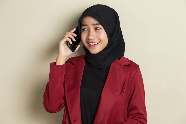 χαρούμενη νεαρή Ασιάτισσα μουσουλμάνα που χρησιμοποιεί κινητό τηλέφωνο - Φωτογραφία, εικόνα