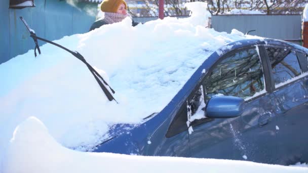 大雪の後、車のブラシで車から女性のクリーニング雪 - 映像、動画