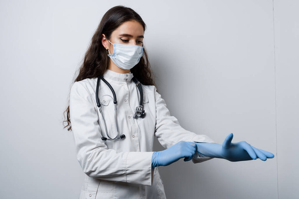 Surgeon wearing medical gloves. Attractive girl in medical mask takes care about her hygiene. Preparation before plastical operation in medical clinic - Fotoğraf, Görsel