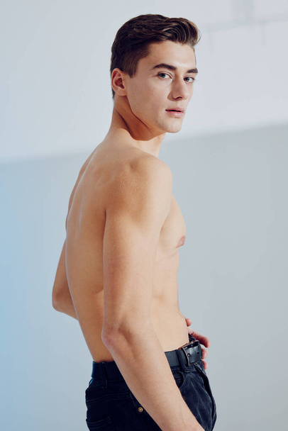 Vista posteriore di un uomo attraente con muscoli pompati sullo stomaco e pantaloni neri - Foto, immagini