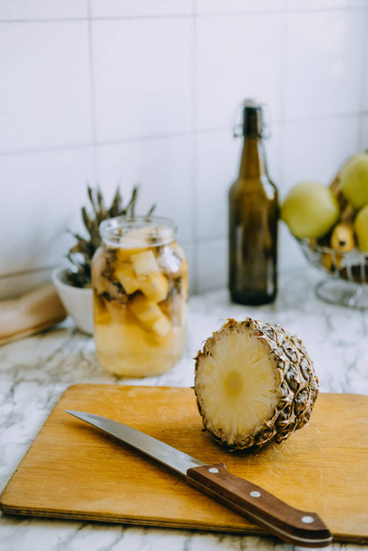 L'ananas fermentato kombucha beve tepache. Processo di cottura della bevanda all'ananas probiotica fatta in casa. Bere barattolo e ananas affettato sulla cucina di casa - Foto, immagini