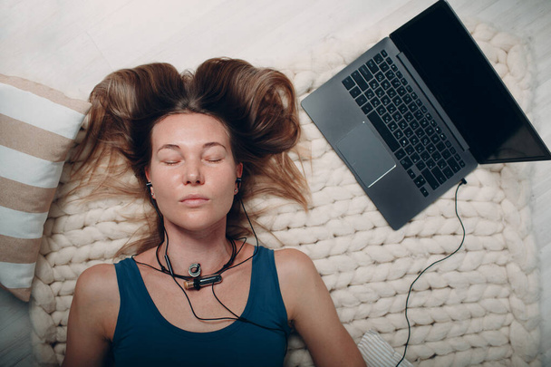 Erwachsene reife Frau macht Yoga Nidra und liegt zu Hause im Wohnzimmer mit Online-Tutorials am Laptop - Foto, Bild