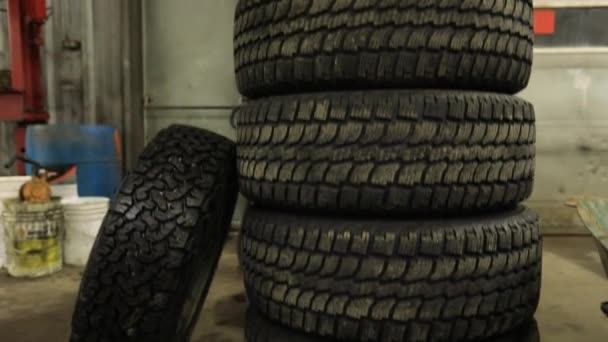 Neumáticos apilados dentro de un taller de reparación de vehículos - Imágenes, Vídeo