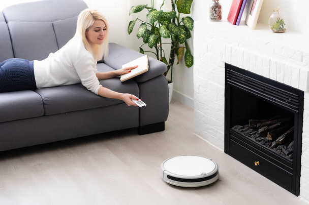 people, housework and technology concept - happy woman and robot vacuum cleaner at home - Valokuva, kuva