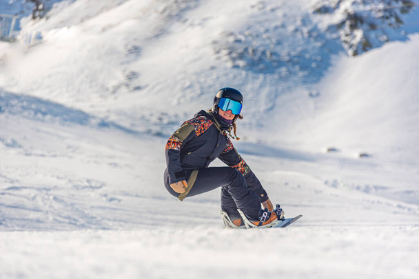 Νεαρή γυναίκα snowboarder σε κίνηση σε snowboard στα βουνά. - Φωτογραφία, εικόνα
