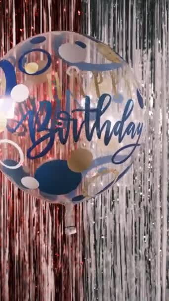 Hyvää syntymäpäivää. Pystysuora laukaus läpinäkyvä helium ilmapallo kirjoitus Hyvää syntymäpäivää taustaa vasten kiiltävä juhlava tinsel, 4k - Materiaali, video