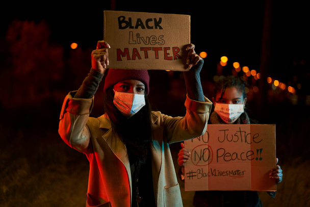 Αφροαμερικανίδες διαδηλώνουν κατά του ρατσισμού. Διαδηλωτές σε μια πόλη με πανό που μάχονται για τα δικαιώματά τους. Μαύρη ύλη ζωής. - Φωτογραφία, εικόνα