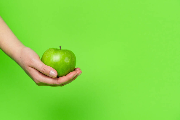Közelkép kéznél tartva zöld alma előtt a háttérben - nagyi kovács egészséges étkezési koncepció másolási hely - Fotó, kép