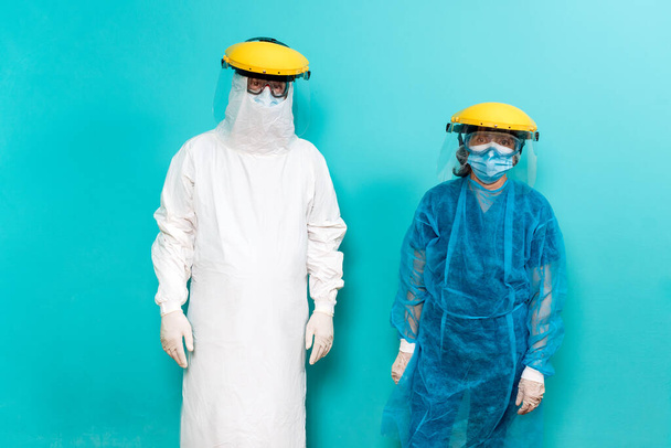 Στοκ φωτογραφία των εργαζομένων στον τομέα της υγείας φορώντας προστατευτική στολή για covid19 κοιτάζοντας κάμερα σε μπλε φόντο. - Φωτογραφία, εικόνα