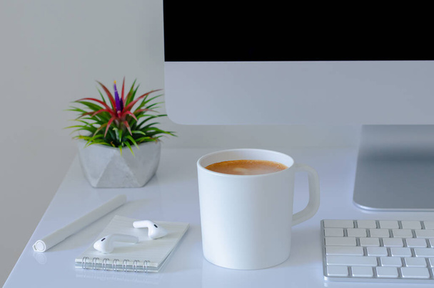 Чашка кофе на рабочем столе с воздушным заводом "Тилландсия" и современными канцелярскими принадлежностями. - Фото, изображение