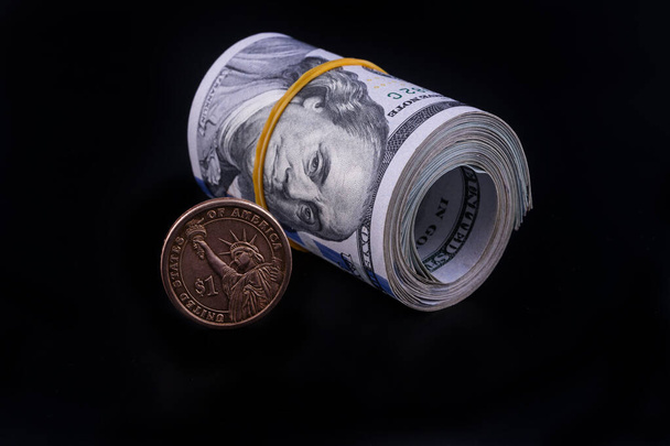 Αμερικανικό νόμισμα ενός δολαρίου με την εικόνα του αγάλματος της ελευθερίας και του συμβόλου του δολαρίου με φόντο θραύσματα χαρτονομισμάτων των 100 δολαρίων  - Φωτογραφία, εικόνα