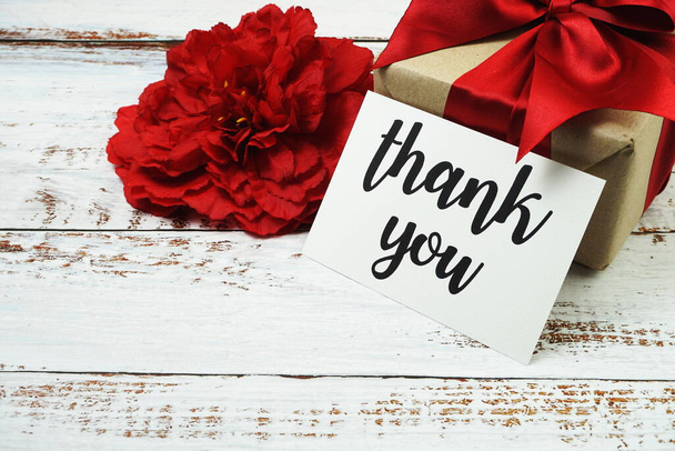 Thank you card with gift box present and flower decoration on wooden background - Valokuva, kuva