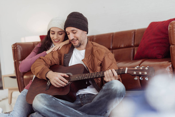 Молодая пара любит играть на гитаре и петь вместе зимой. пара любит в свитере наслаждаться и играть музыку вместе. Счастливая влюбленная пара. - Фото, изображение