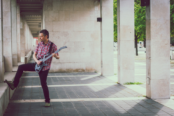 Man in short sleeve shirt playing electric guitar - Foto, imagen