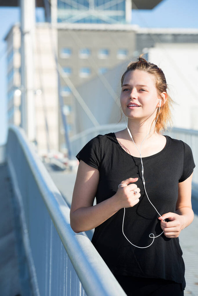 Female running and listening music on city bridg - Φωτογραφία, εικόνα