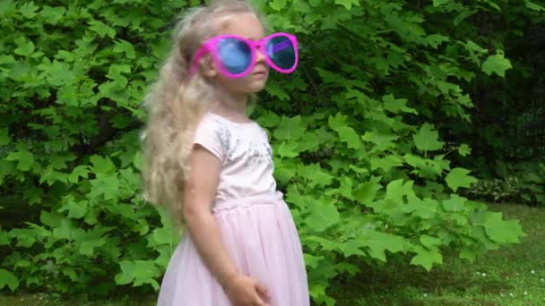 遊び心のある子供たち、男の子と女の子が屋外で巨大なサングラスをかけています。ジンバル・モーション - 映像、動画