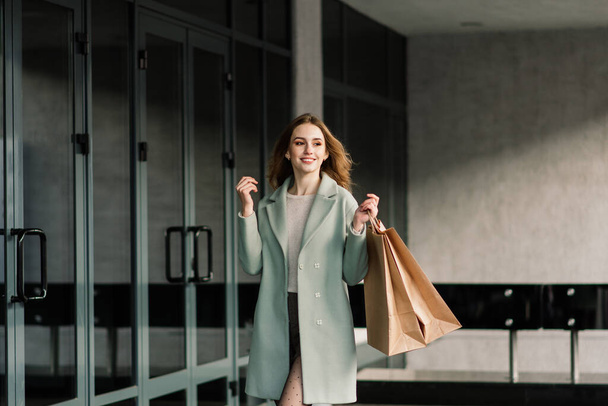 Portrait of cheerful young lady holding shopping bags outdoor - Фото, изображение