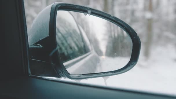 Voyage d'hiver. Rétroviseur latéral de la voiture réfléchissant la route enneigée - Séquence, vidéo