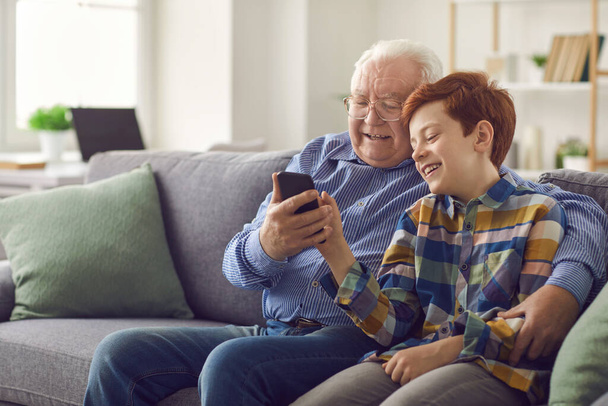 Grandson showing grandpa how to use social media or make video call on mobile phone - Foto, Imagem