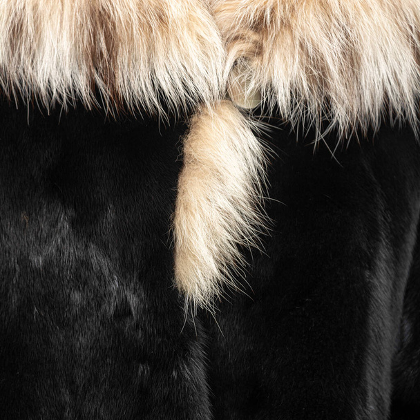 Fourrure foncée sur un manteau de fourrure avec un col clair moelleux. Modèle brillant coûteux avec des poils texturés - Photo, image