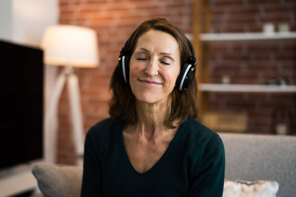 Smiling Woman Listening Music Using Headphones In Living Room - Фото, изображение