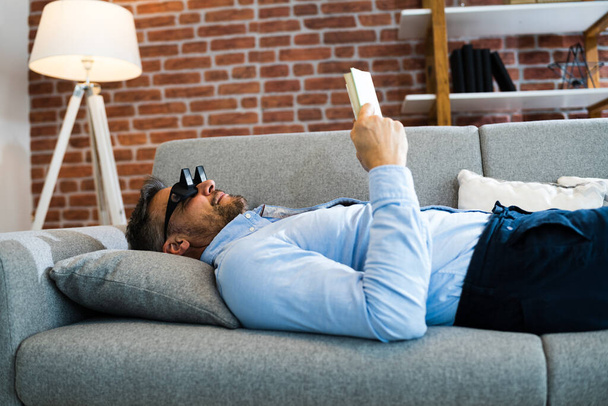 Man Using Lazy Reading Prism Glasses To Read Book - Φωτογραφία, εικόνα