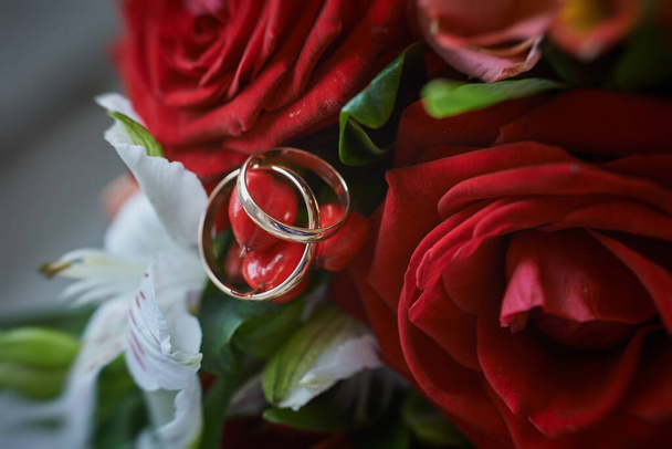 gold rings and a beautiful bridal bouquet of roses on the background. details, wedding traditions. close-up, macro - Photo, Image