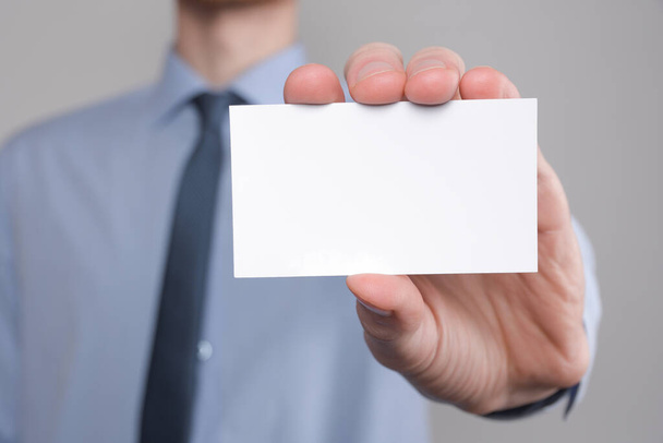 Businessman ,Business Man's hand hold showing business card - close up shot on grey background. Show a blank piece of paper. Paper visit card. - Foto, Imagen