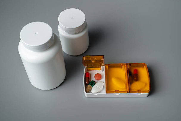 Tablette boîte avec des pilules sur un fond gris. Tablettes pour demain, déjeuner et dîner. Prévention des maladies - Photo, image