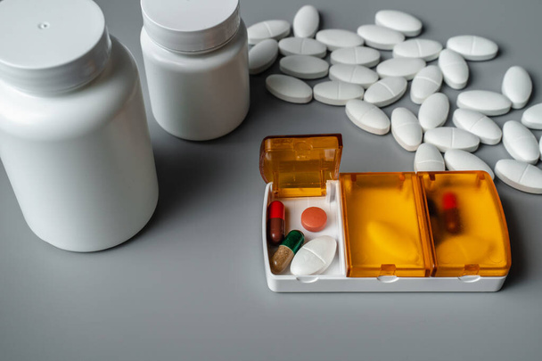 Tabletdoos met pillen op een grijze achtergrond. Tabletten voor morgen, lunch en diner. Ziektepreventie - Foto, afbeelding