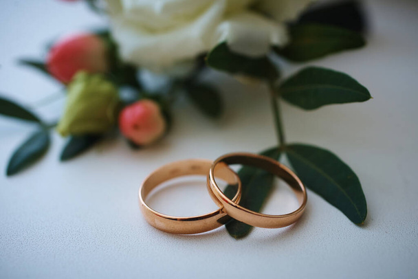 gold rings and a beautiful bridal bouquet of roses on the background. details, wedding traditions. close-up, macro - Fotó, kép