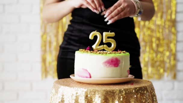 Belle femme caucasienne en robe de soirée noire allumant 25 bougies d'anniversaire sur gâteau - Séquence, vidéo