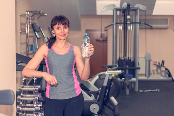 girl in the fitness room drinking water, tone - Foto, Bild