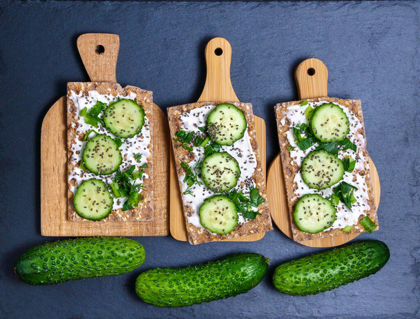 Healthy dietary breakfast of crisps rye flat toast with fresh vegetables green cucumber, cream cheese. flat lay - Photo, Image