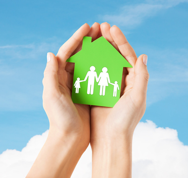 Mãos segurando casa verde com a família
 - Foto, Imagem