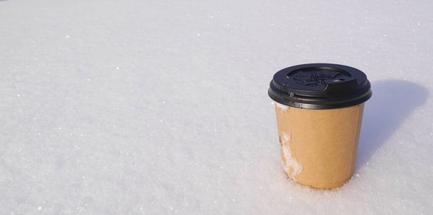 Paper cup with aromatic, hot latte coffee on fluffy, frosty snow. Aromatic composition with natural. - Photo, Image