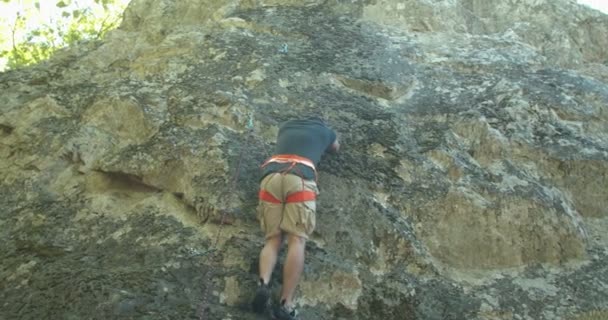 Ο άνθρωπος σκαρφαλώνει στα βράχια μια ηλιόλουστη μέρα - Πλάνα, βίντεο