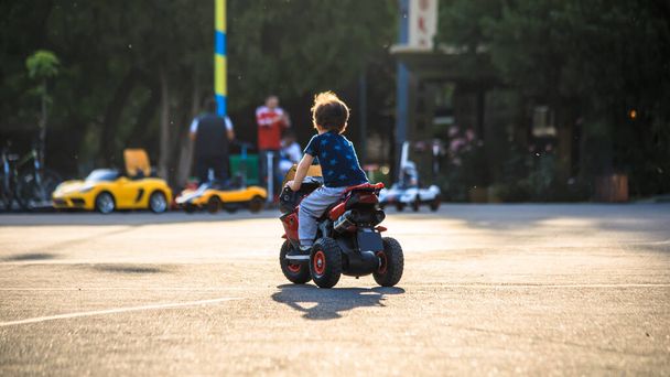 Boy riding big red toy car in par - Фото, зображення