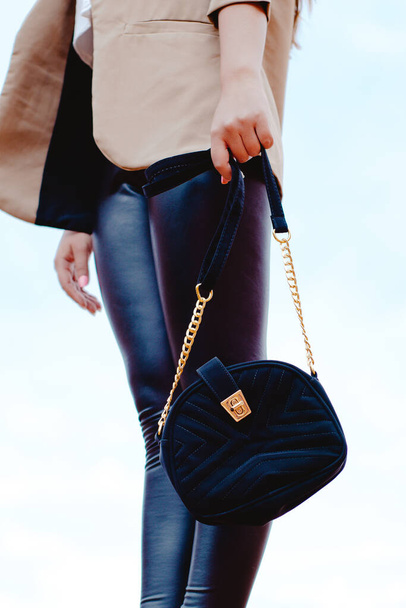 A vertical shot of a female with leather pants holding a velvet fashionable bag - Valokuva, kuva