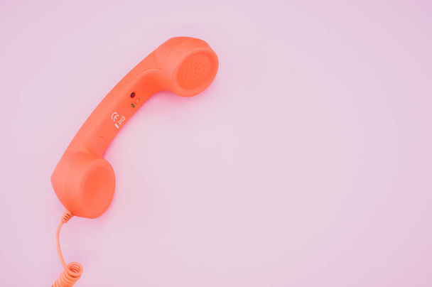 A high angle shot of a vintage orange telephone on a pink usrfa - Photo, image