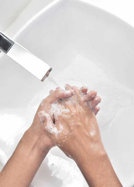A vertical top view of hands with soap near a sink - Fotó, kép