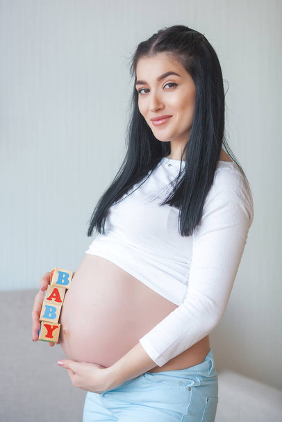 Giovane donna incinta in casa. Aspettativa femminile - Foto, immagini