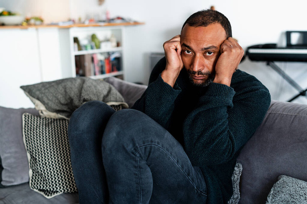 Депресивний 40-річний чоловік сидить на дивані вдома
 - Фото, зображення