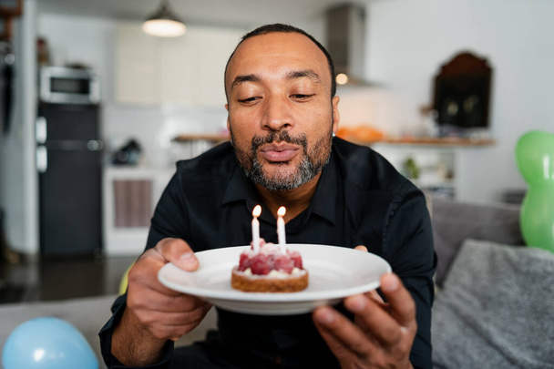 Handsome 40 years old man blowing candles on his birthday cake - Foto, Imagen