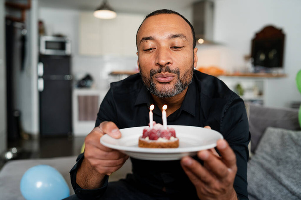 Hezký 40 let starý muž foukání svíčky na jeho narozeninový dort - Fotografie, Obrázek
