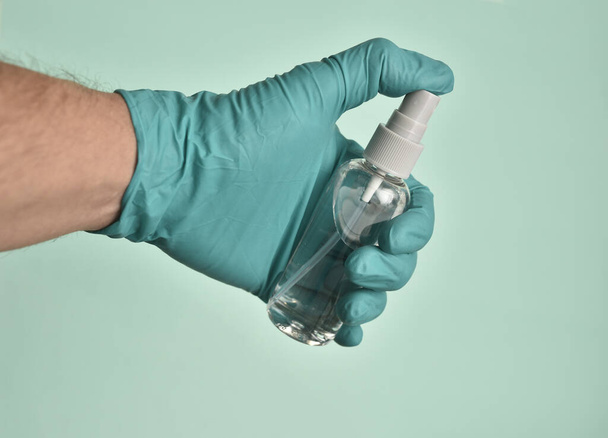 A closeup shot of a gloved hand holding a bottle of sanitizer - Zdjęcie, obraz