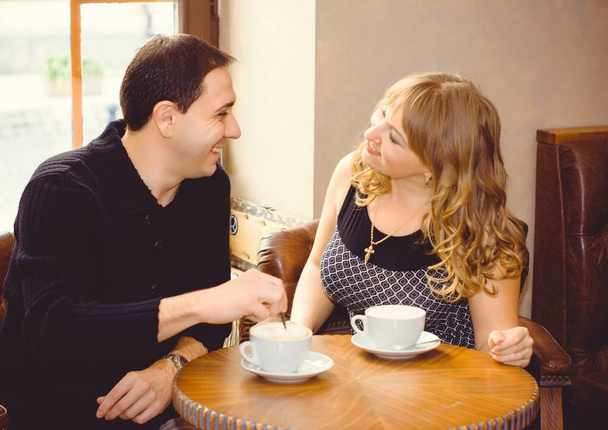 Zamilovaný pár středního věku sedí v kavárně, pije kávu, baví se a tráví spolu čas. Radostný milující dospělý pár odpočívající doma v zimě ráno - Fotografie, Obrázek