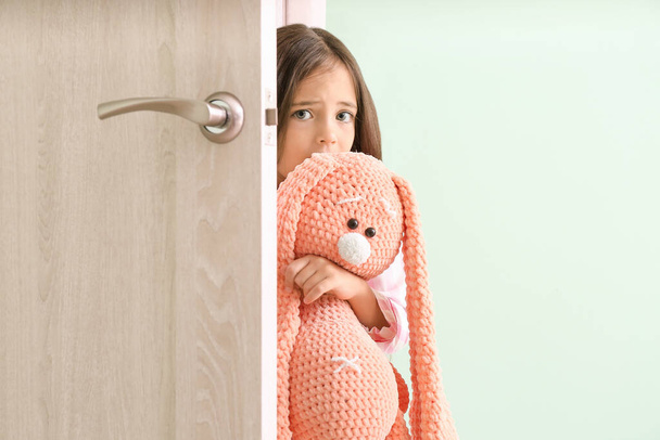 Verängstigtes kleines Mädchen schaut aus der Tür - Foto, Bild